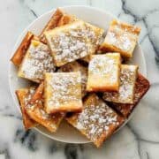 top down view of ooey gooey bars sprinkled with powdered sugar piled on plate