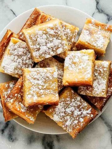 top down view of ooey gooey bars sprinkled with powdered sugar piled on plate