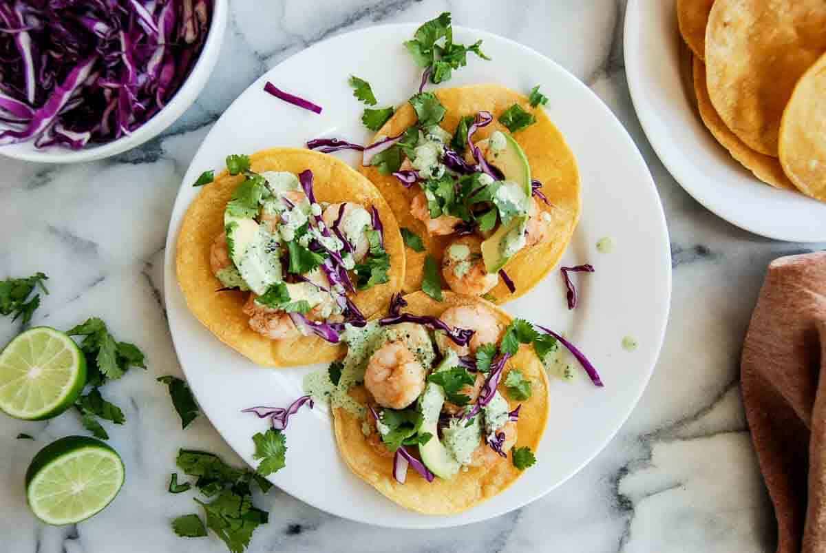 3 shrimp tostadas on plate with cilantro lime sauce.