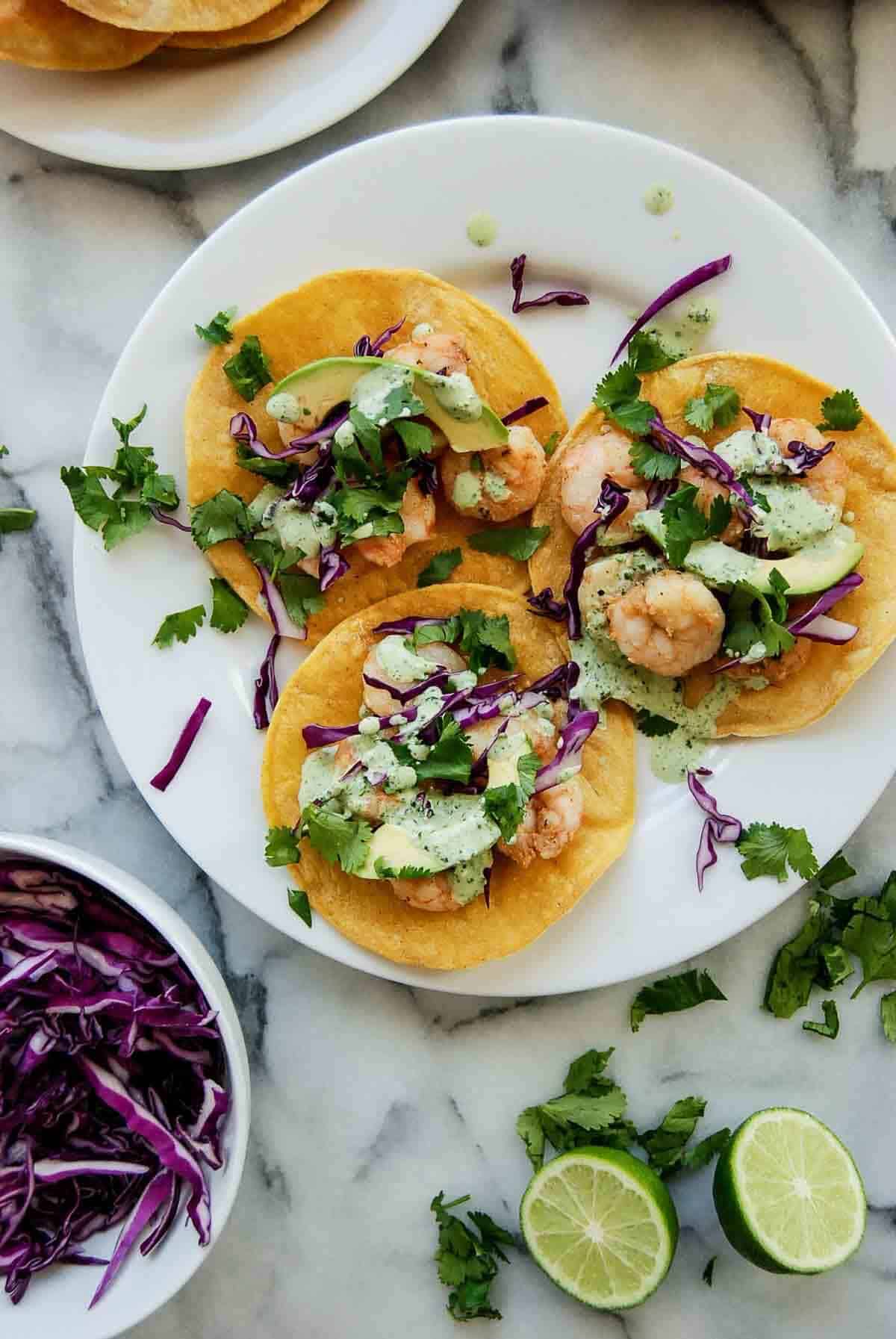 3 shrimp tostadas on plate with cilantro lime sauce.
