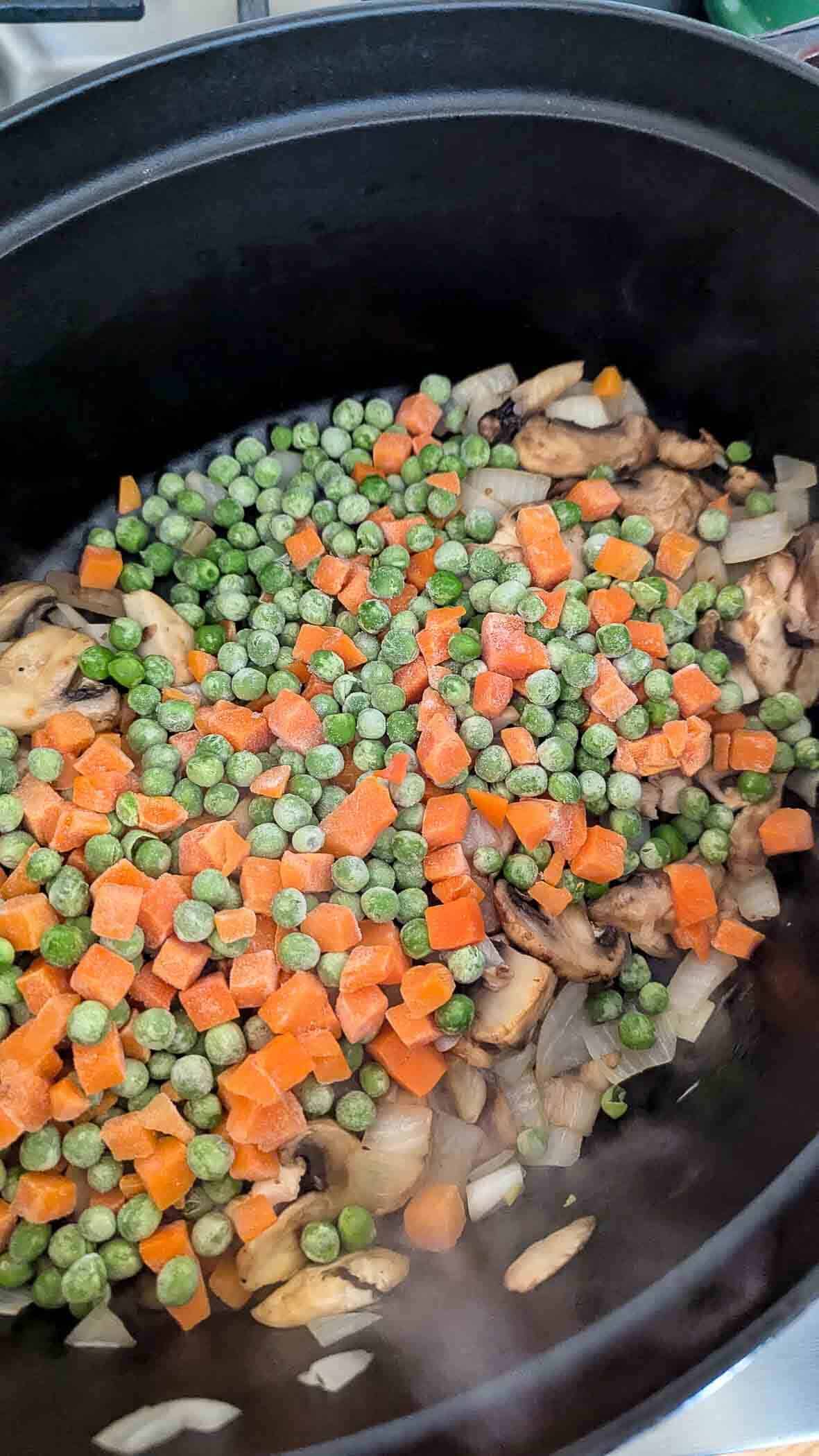onions and mushrooms in dutch oven with frozen peas and carrots.