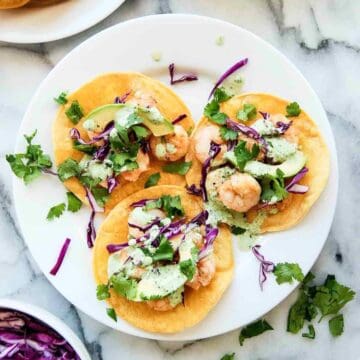 Shrimp tostadas on plate with cilantro lime cream sauce.