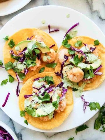 Shrimp tostadas on plate with cilantro lime cream sauce.