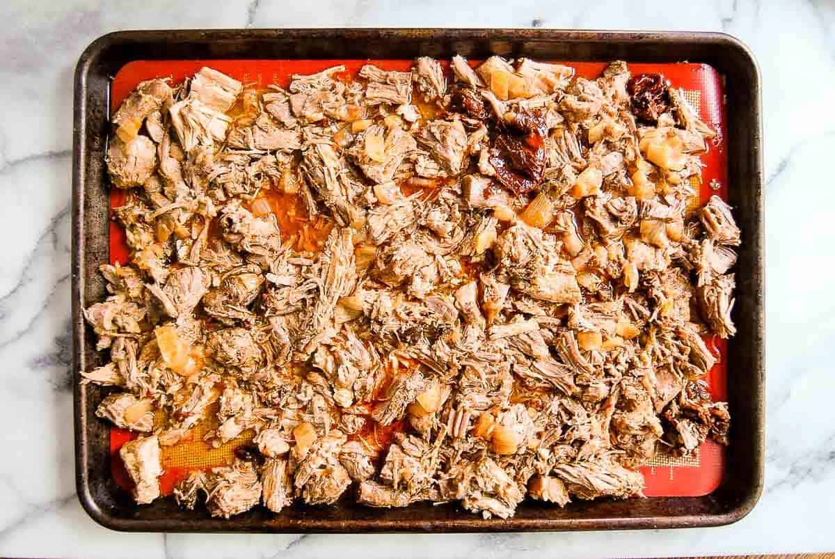 cooked pork carnitas on baking tray ready for broil.