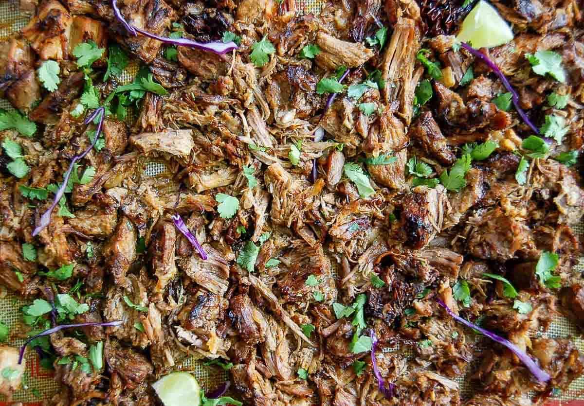 crispy pork carnitas on baking tray with cilantro and lime.