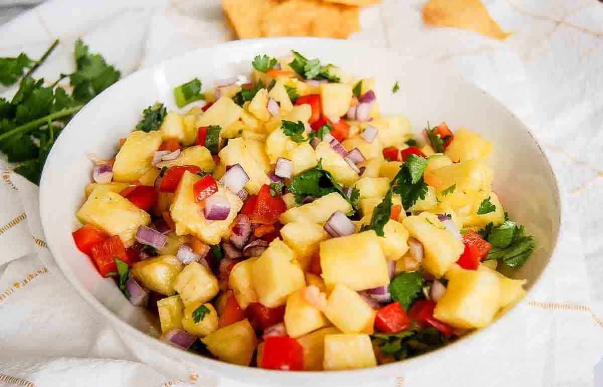 side view of pineapple habanero salsa in bowl with chips on the side.
