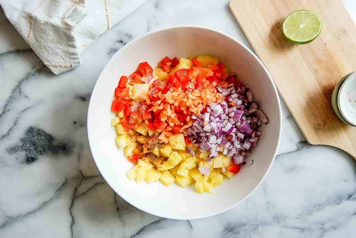 red pepper, pineapple, red onion, habanero and spices in mixing bowl.