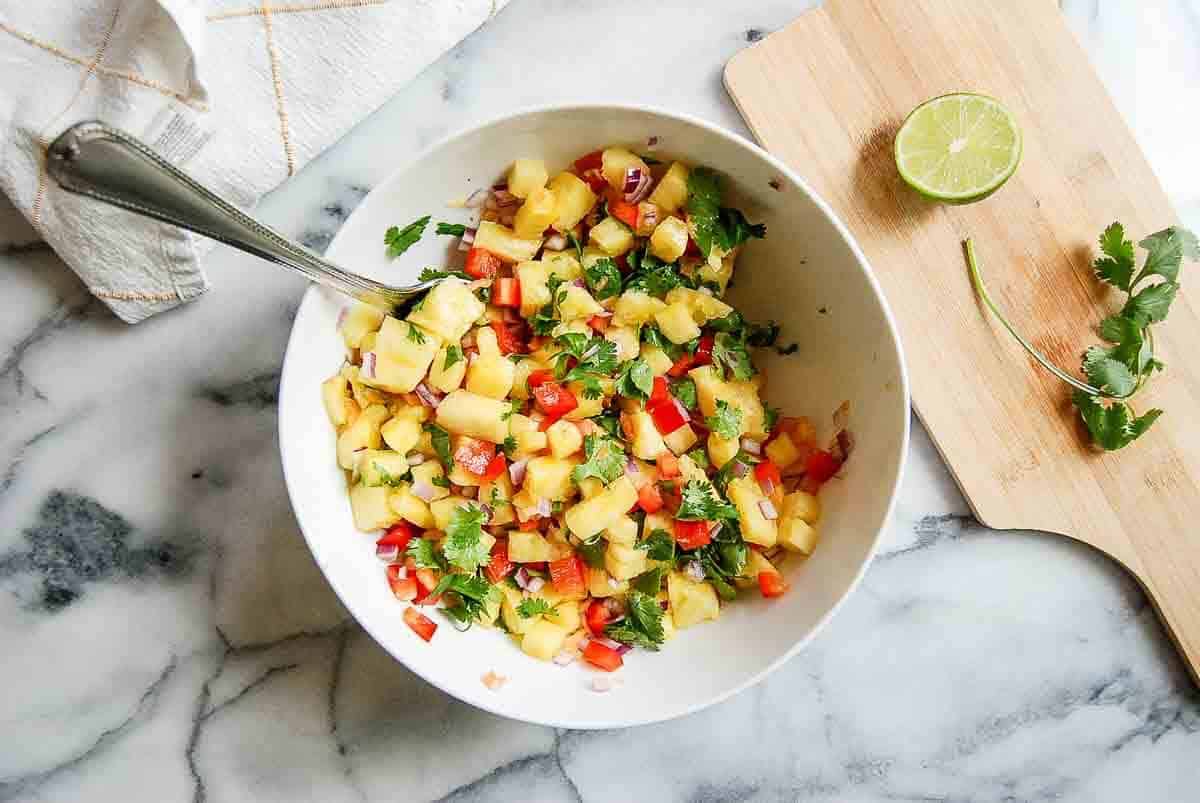 combined pineapple habanero salsa in mixing bowl with spoon on countertop.
