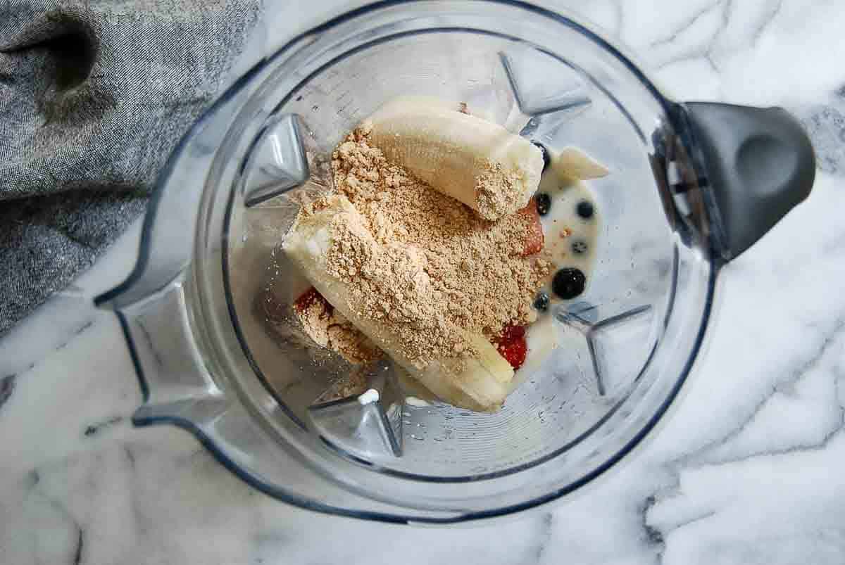 A blender filled with bananas, blueberries and other ingredients.