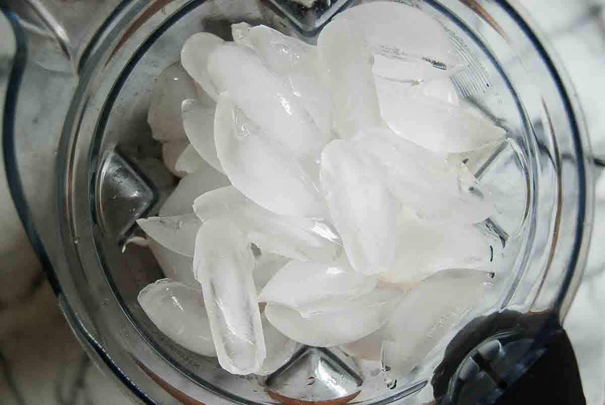 A close-up view from above with ingredients for virgin pina colladas inside a blender, ready to be blended.