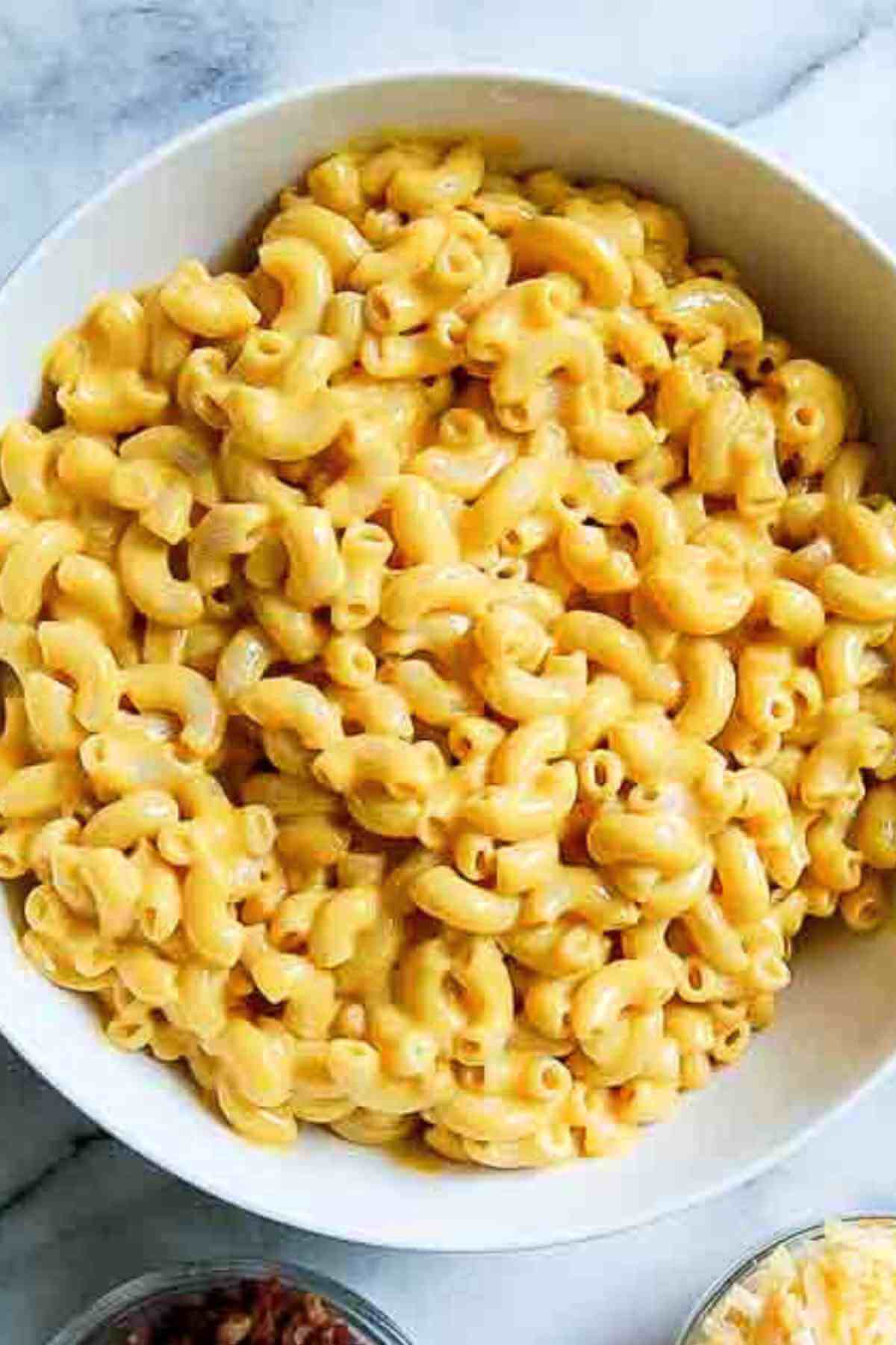 A close-up of a bowl filled with creamy macaroni and cheese on a marble surface.