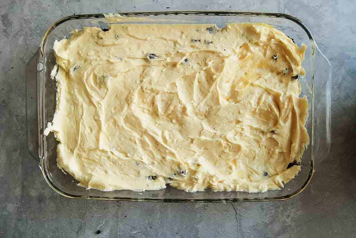 Rectangular glass baking dish filled with smooth, vanilla pudding mixture a top crushed oreo cookies.