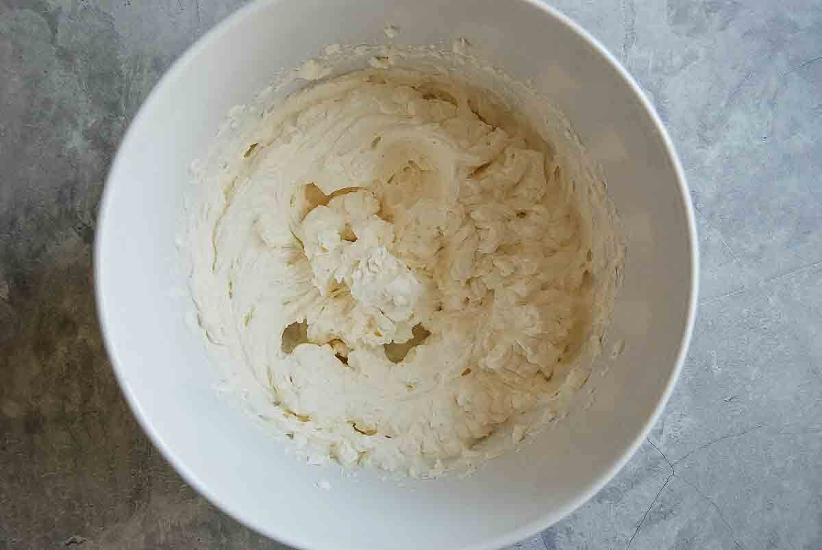 A white mixing bowl filled with homemade whipped cream.