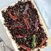 A class casserole dish filled with dirt cake topped with colorful gummy worms.