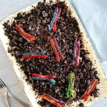 A class casserole dish filled with dirt cake topped with colorful gummy worms.