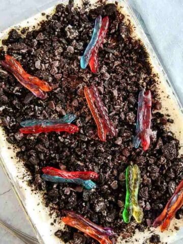 A class casserole dish filled with dirt cake topped with colorful gummy worms.