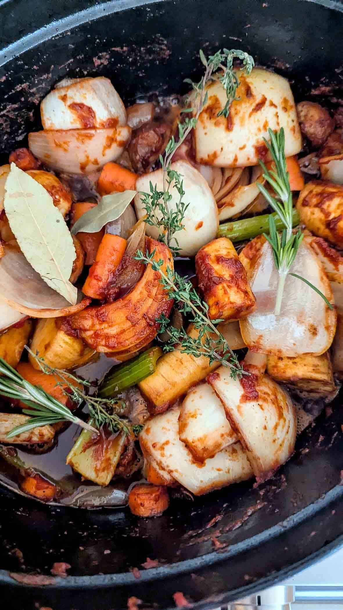 A close-up of a dutch oven filled with a pot roast and chopped vegetables.