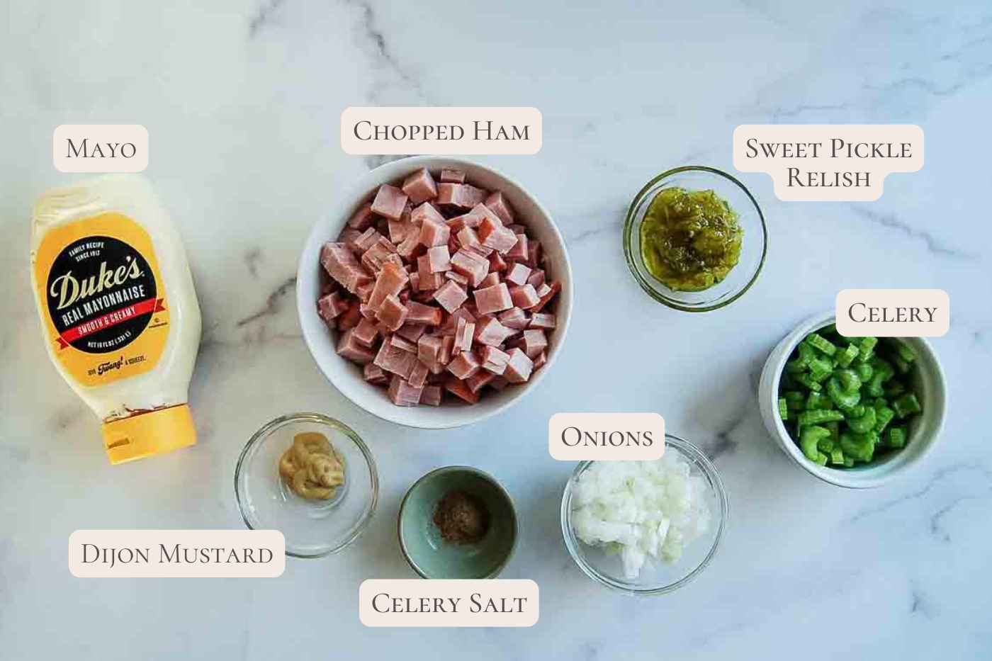 Ingredients for ham salad on a marble surface.