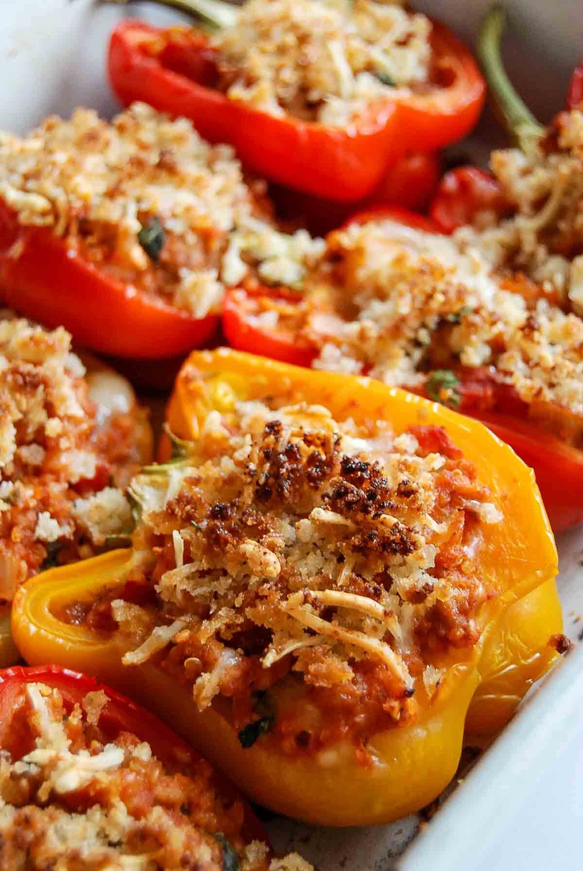 Close-up of baked turkey stuffed bell peppers, filled with a turkey and vegetable mixture, topped with golden-brown breadcrumbs and melted cheese, arranged in a white baking dish.