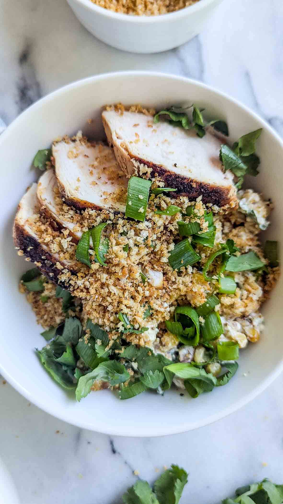 a street corn chicken rice bowl on a marble surface.