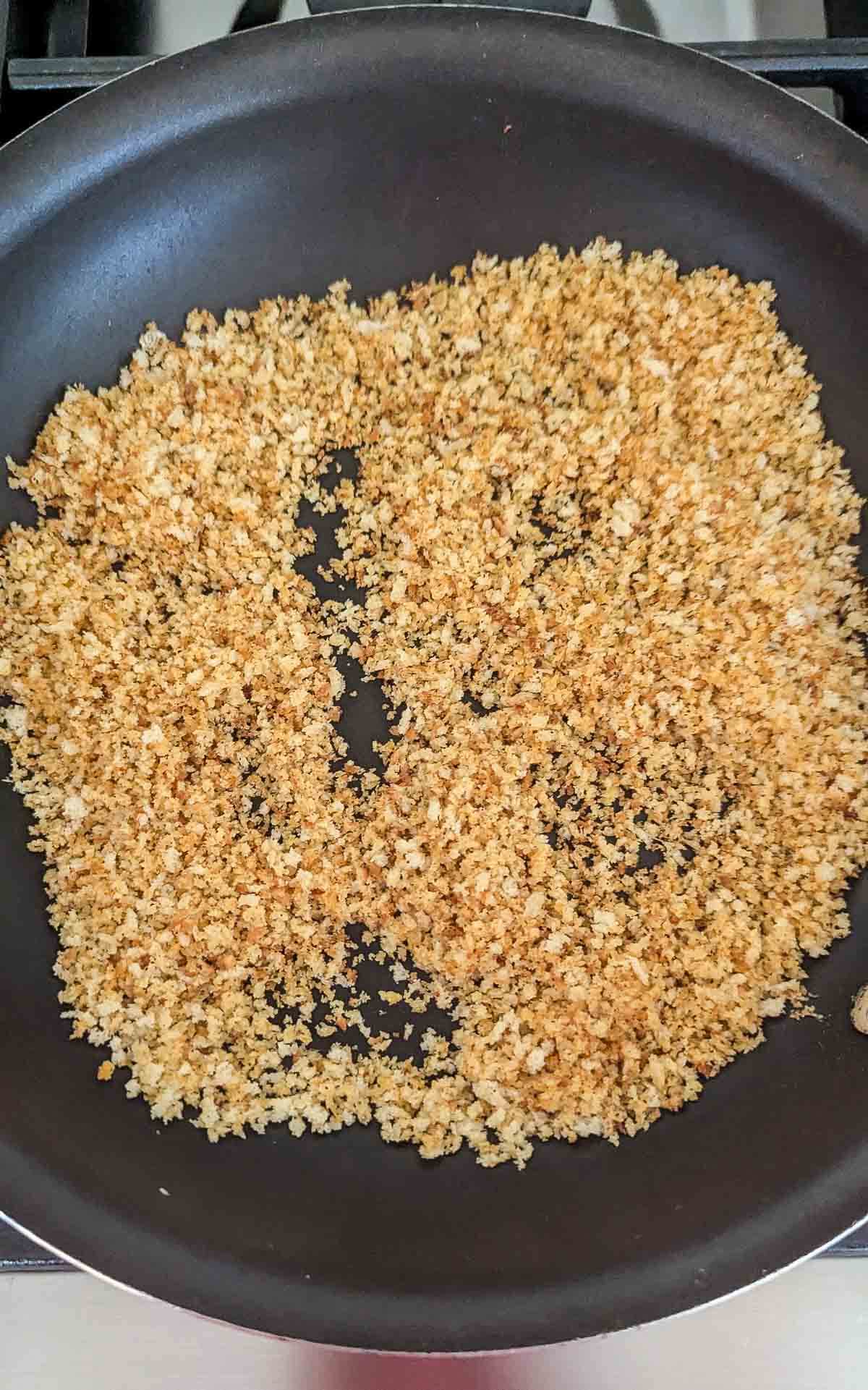 Toasted panko breadcrumbs spread evenly in a black skillet.