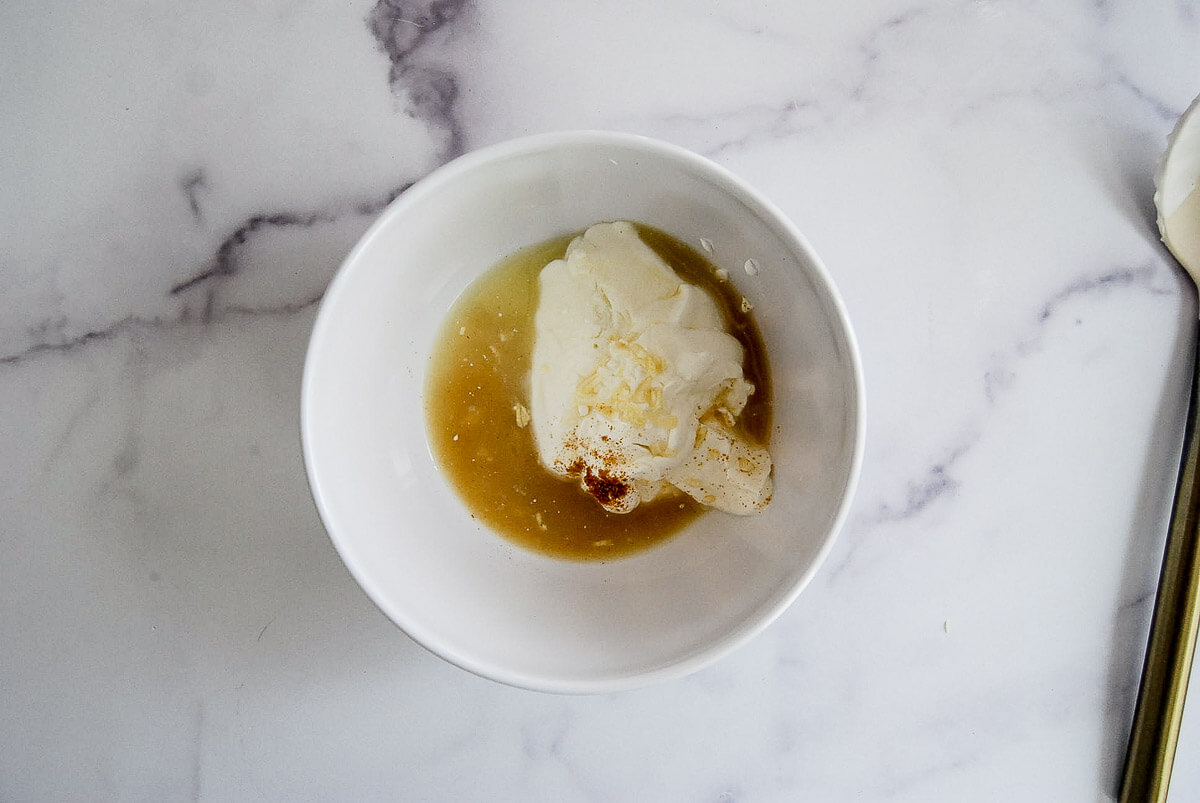 A white bowl on a marble surface containing ingredients for lime crema.
