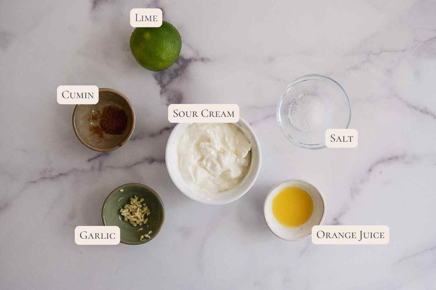 A marble surface with labeled ingredients for lime crema.