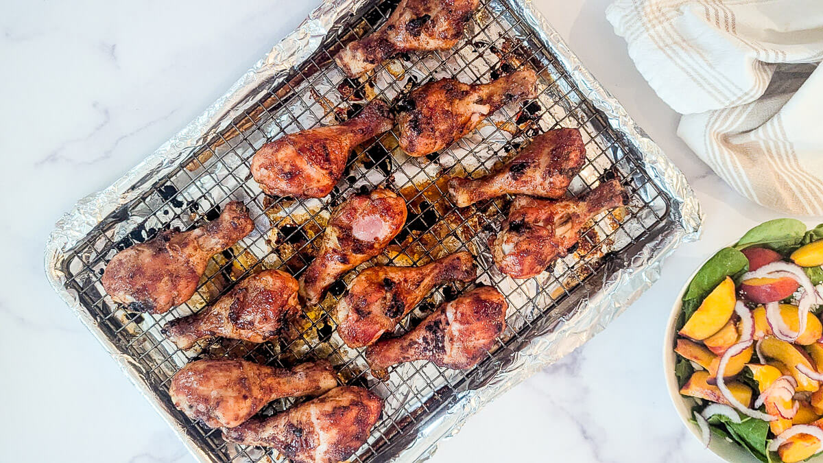Baked BBQ chicken drumsticks on a foil-lined wire rack.