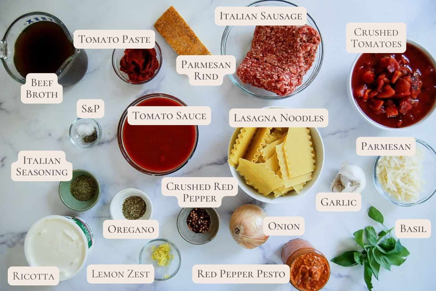 Top-down view of labeled lasagna soup ingredients in bowls and jars, including beef broth, tomato sauce, Italian sausage, ricotta, lasagna noodles, spices, onion, garlic, cheese, and basil on a white surface.